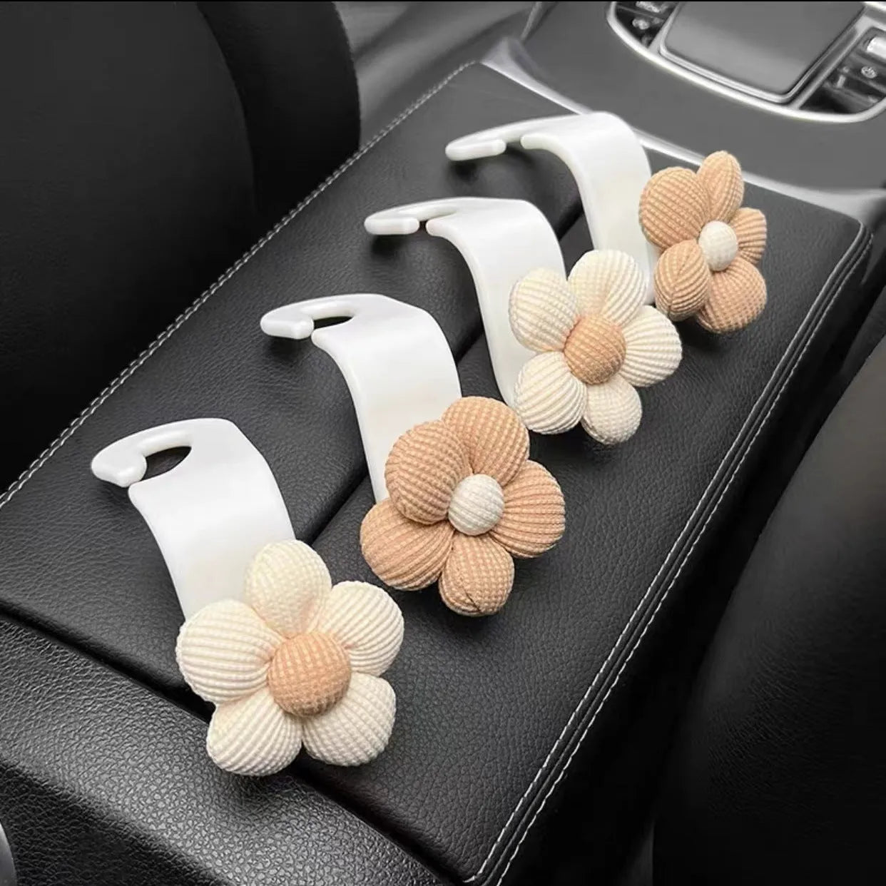 Khaki-coloured plastic car seat hook with a small decorative flower for storage.