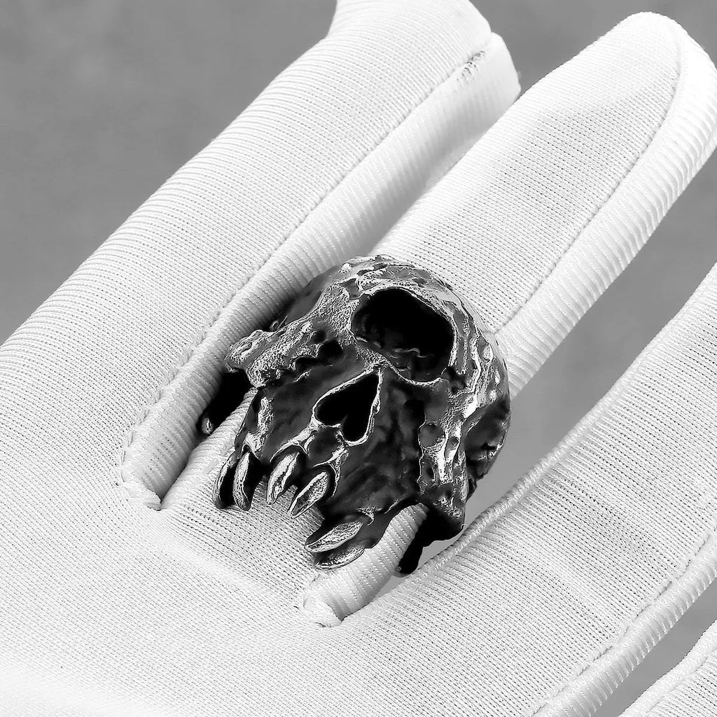 A close-up of a silver-toned alloy ring featuring a detailed one-eyed skull design.