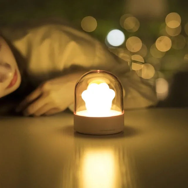 Grey cat paw shaped USB rechargeable musical night light on a wooden desk