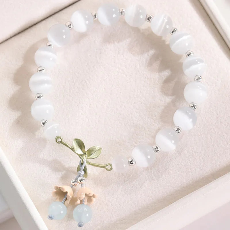 Close-up of a women's opal cat's eye stone beaded bracelet with diamond-shaped beads on a wrist.