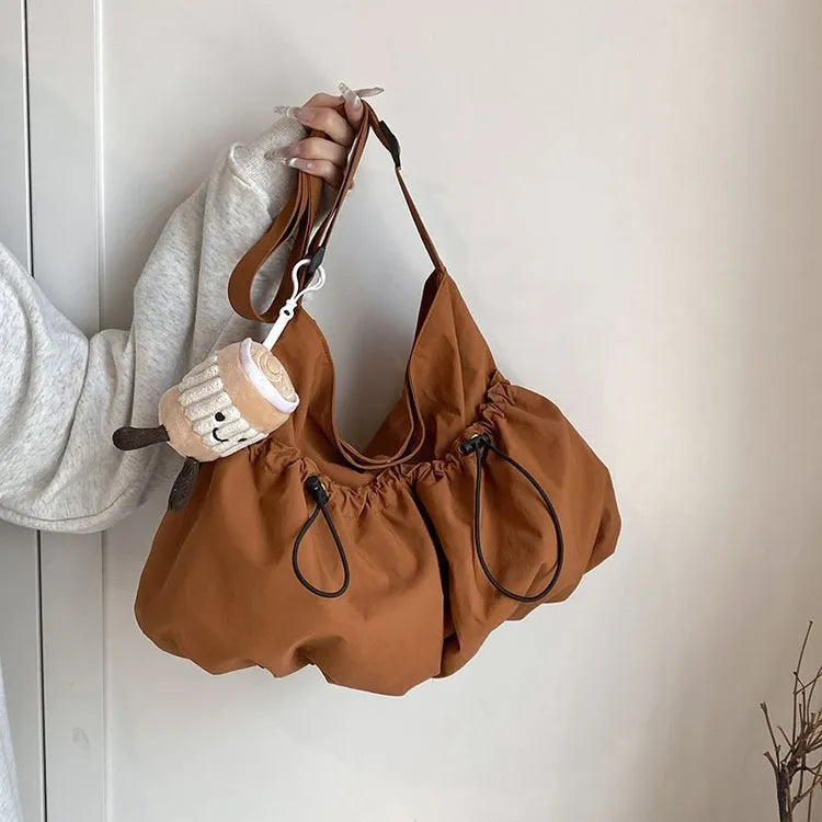 Soft foldable polyester crossbody bag in beige colour showing split pocket and crossbody strap.