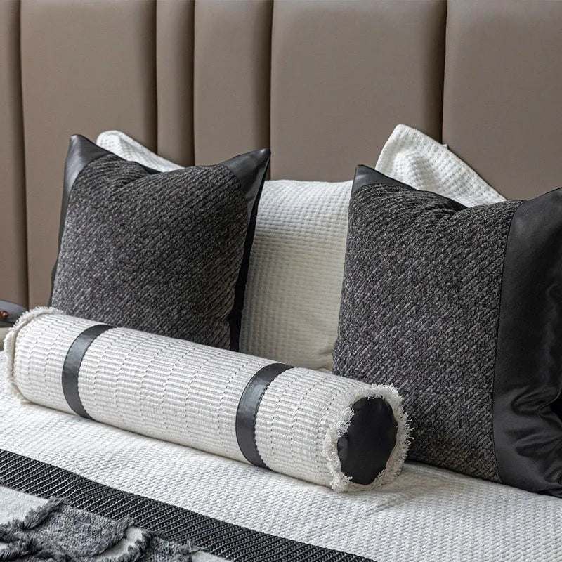 Modern grey and white plaid bed runner blanket set with round leather pillow on a bed.