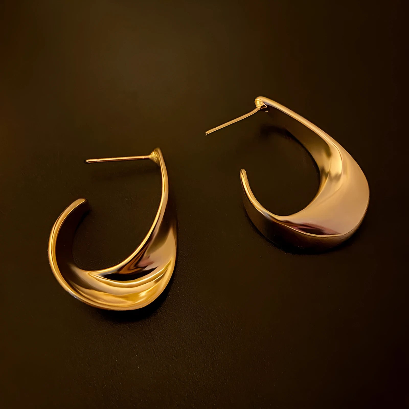 A pair of twisted geometric round metal earrings with a gold electroplated finish on a white background.