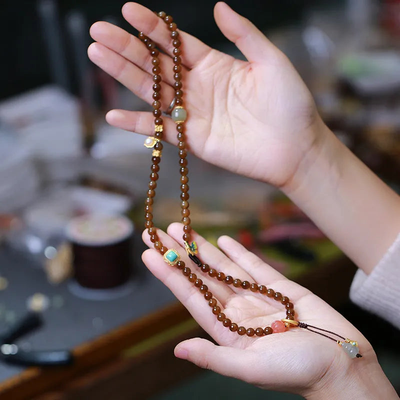 Brown Hetian Jade three-ring bracelet with butterfly and gourd charms on a wrist.