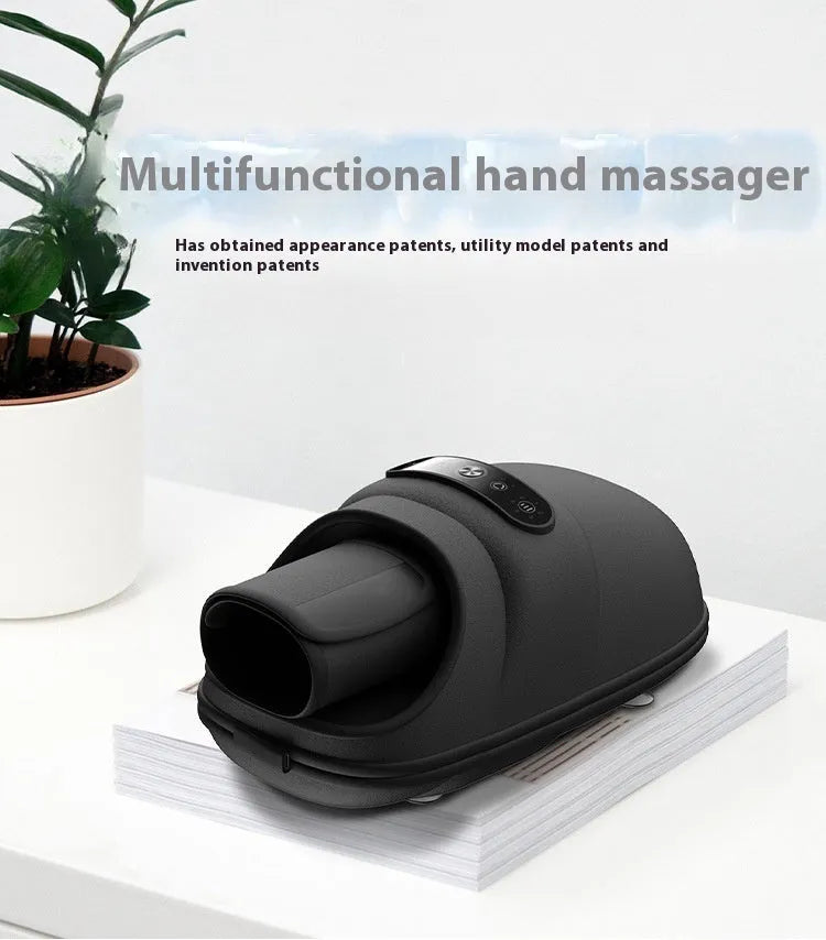 Intelligent electric hand massager with hot compress in black colour, multi-point massage pads, and USB charging cable on a desk
