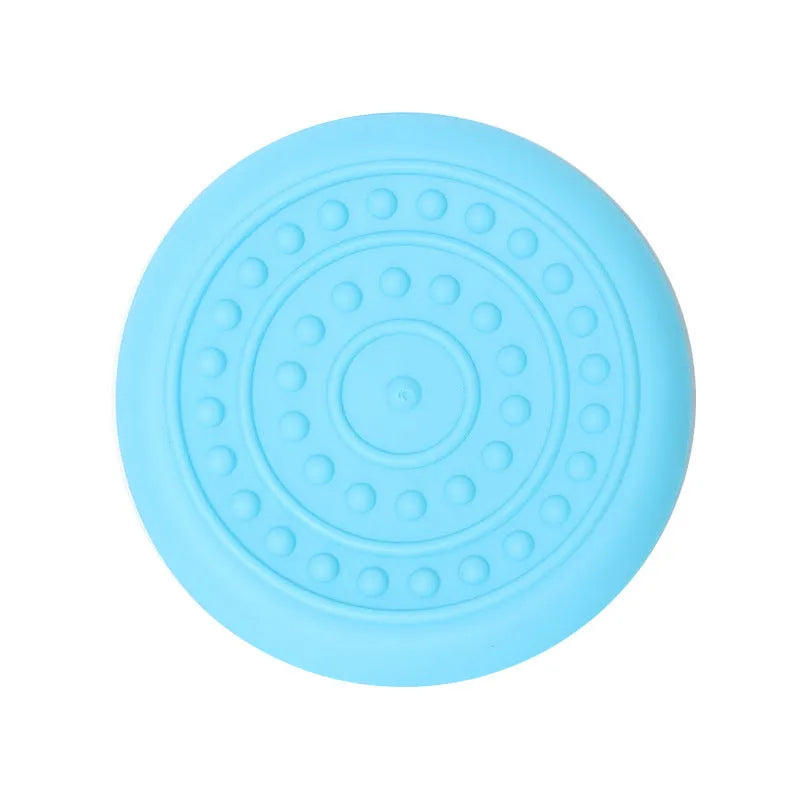 Plastic dog flying disc toy in green, shown on grass for scale