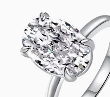 Oval gemstone ring in silver with four-claw setting on a model's hand.