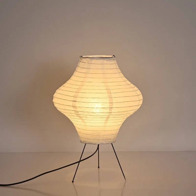Japanese style table lamp with a white paper shade and a wooden base on a table.