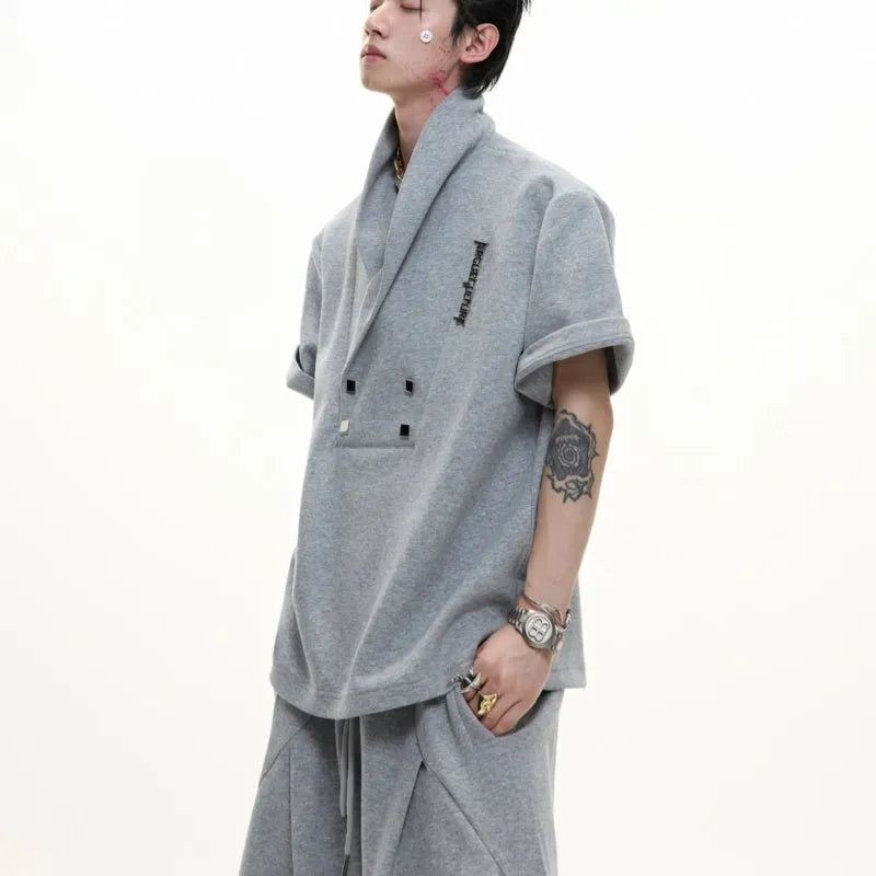 Men's dark grey cotton sports suit with V-neck short-sleeve jacket, padded shoulders, metal embellishments, and matching shorts.