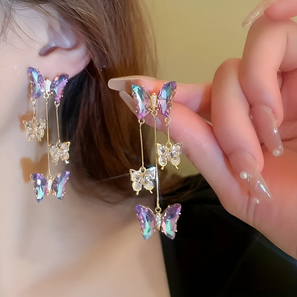 Silver Needle Blue Purple butterfly and crystal flower tassel drop earrings on a white background.