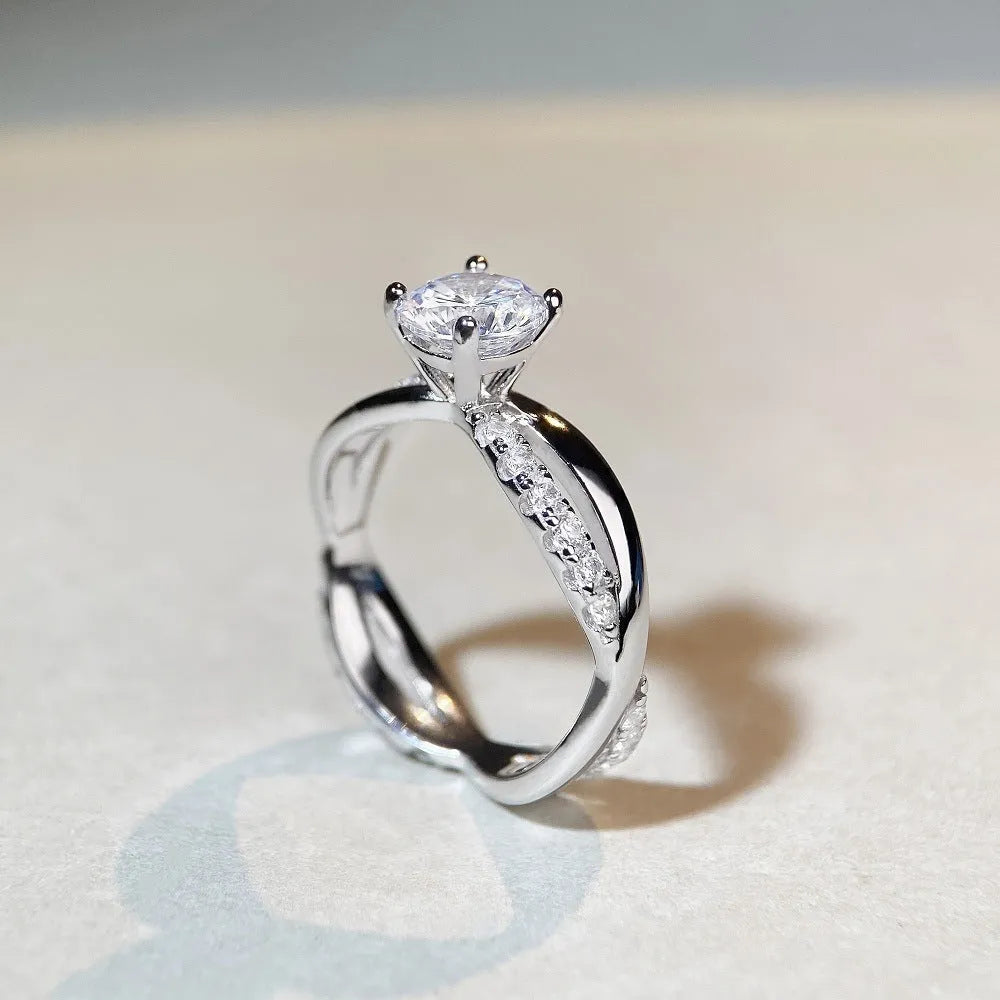 Silver ring with 1 karat moissanite in four-claw setting on a geometric twisted arm band.