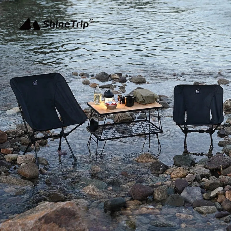 Lightweight aluminium folding moon chair in a garden setting, shown in sand colour with a high back.