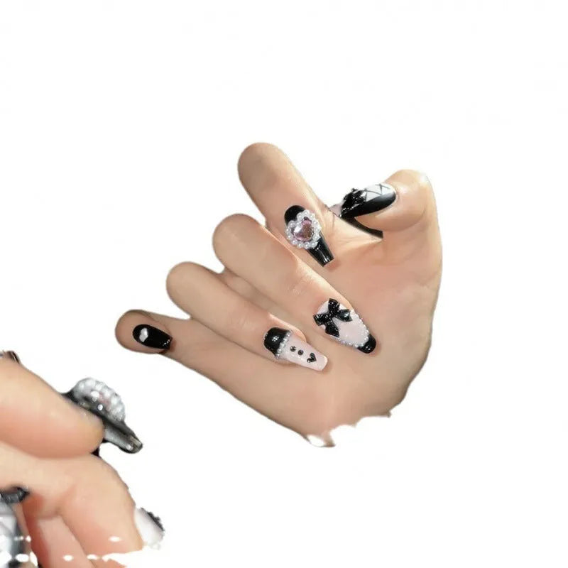 Hand-painted black and pink heart design on detachable plastic manicure nails in cat's eye style.