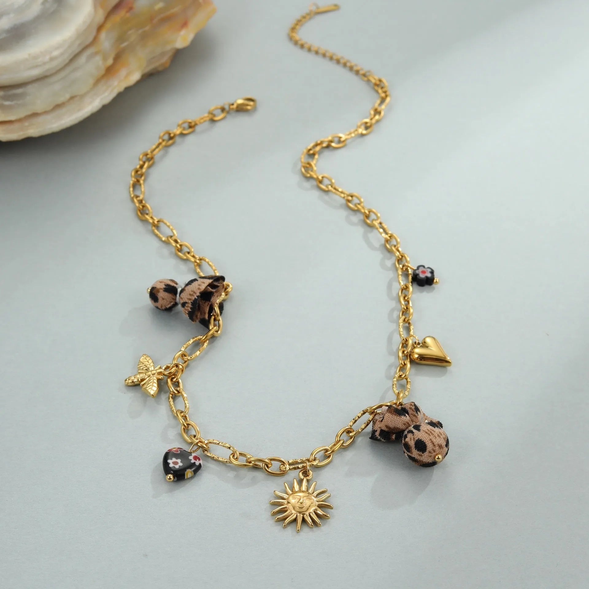 Stainless steel necklace with a geometric leopard pendant and heart and flower accents on an adjustable chain.