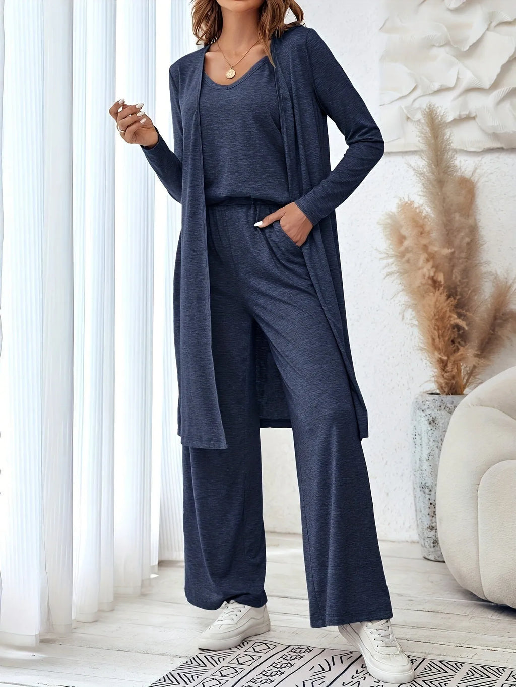 Blue women's three-piece suit with sling top, long cardigan, trousers, and suspenders on a mannequin.