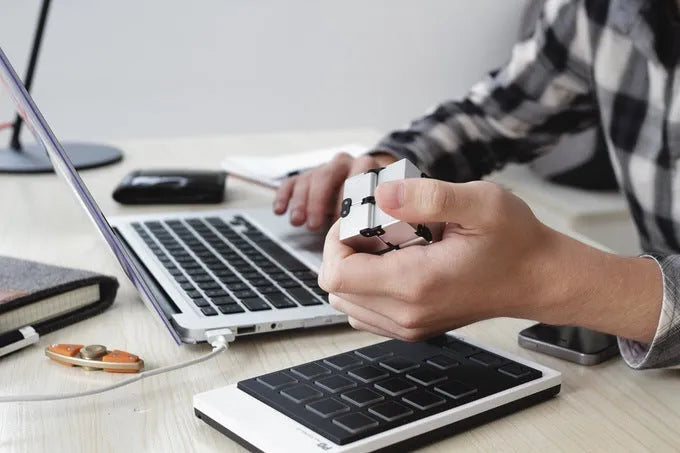 Zinc alloy infinity cube fidget toy showing black and silver rotating cube puzzle on a desk.