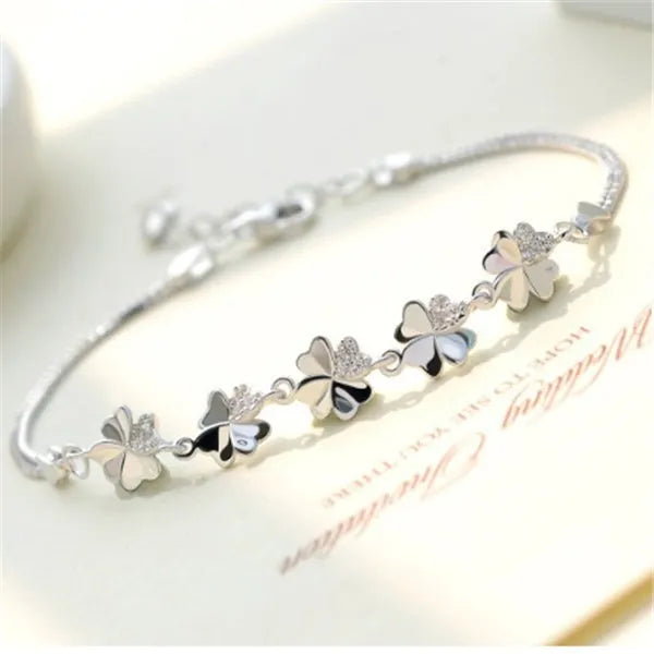 Silver four-leaf clover bracelet with adjustable chain on white background