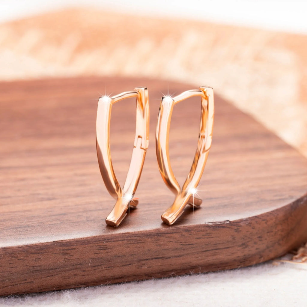 A pair of rose gold cross-shaped earrings made from copper.