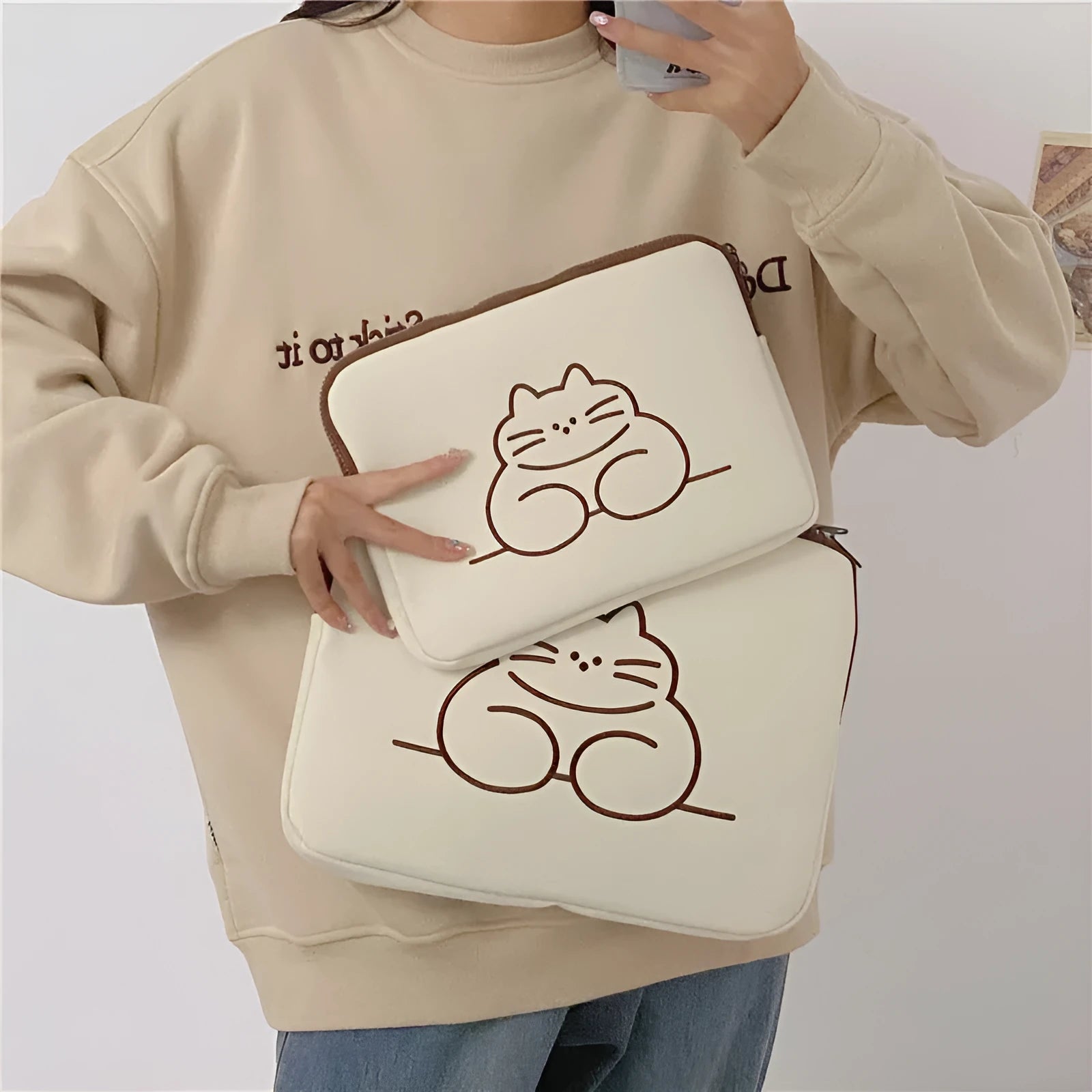 Embroidered fat cat design on a navy blue nylon tablet protective sleeve with a black zipper.