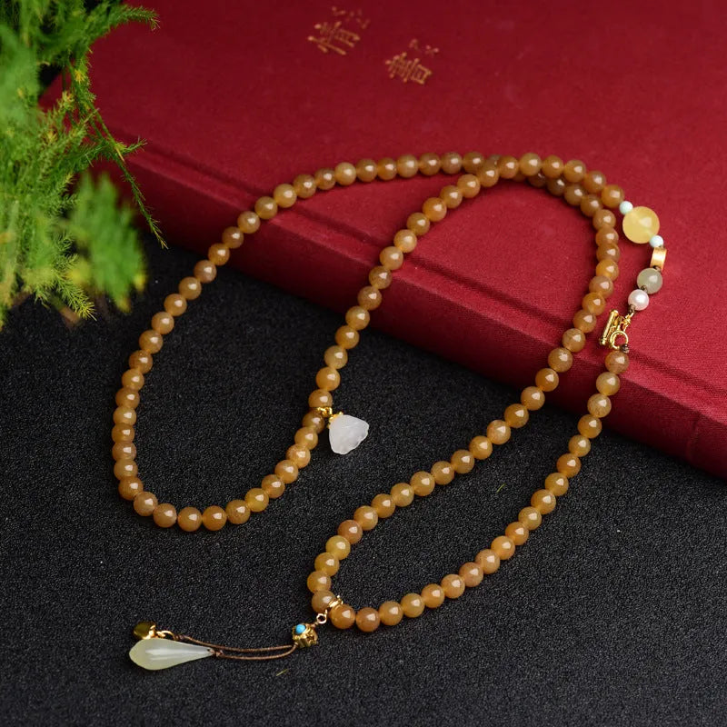 Women's jade bracelet with 6mm round beads showing clear water green pine pattern and leaf sequin accents