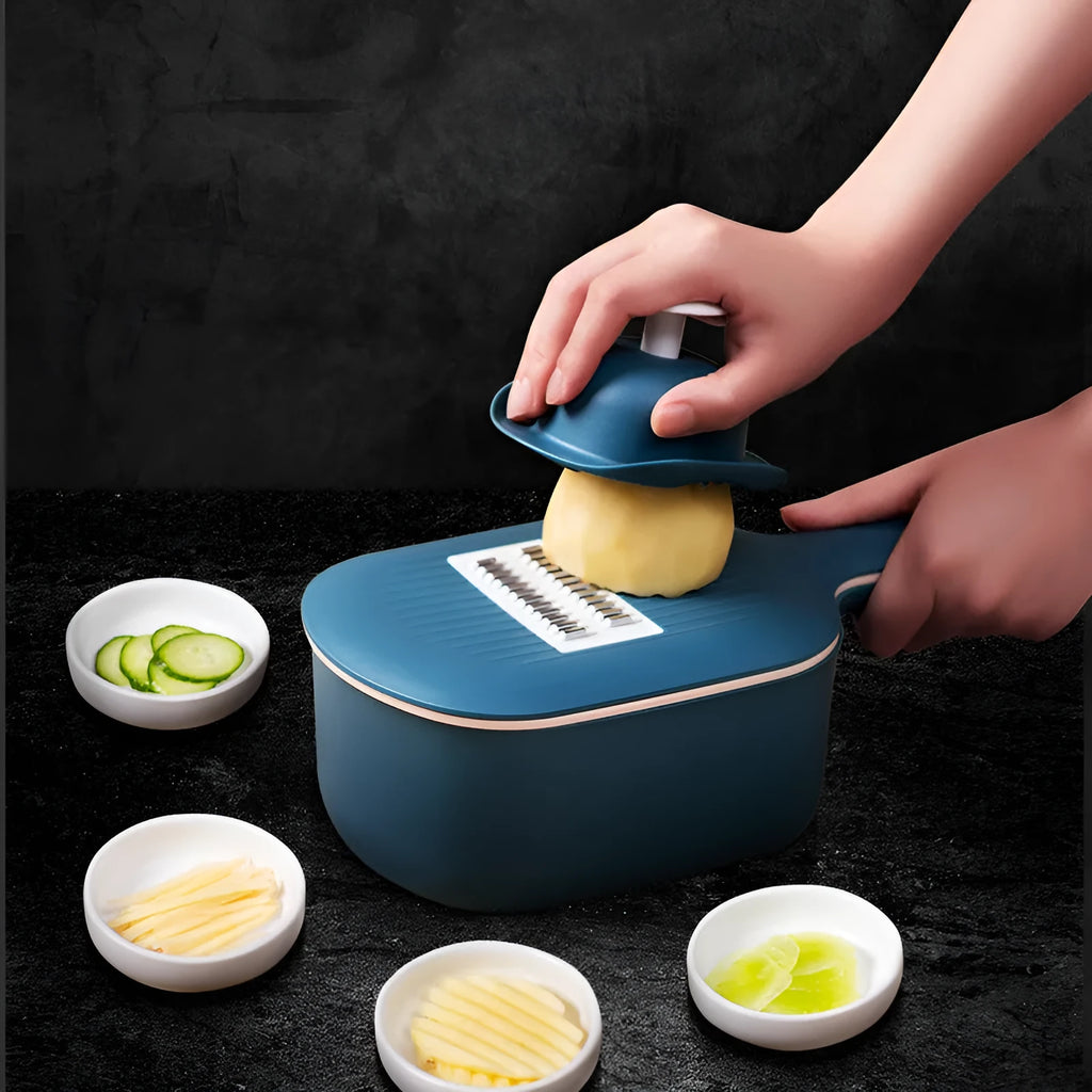 Dark blue scoop vegetable cutter with four stainless steel blades, hand guard and drain basket on a kitchen worktop