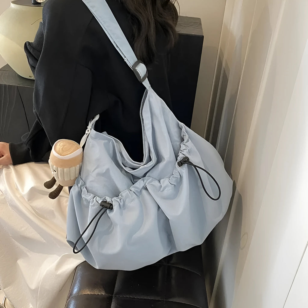 Soft foldable polyester crossbody bag in beige colour showing split pocket and crossbody strap.