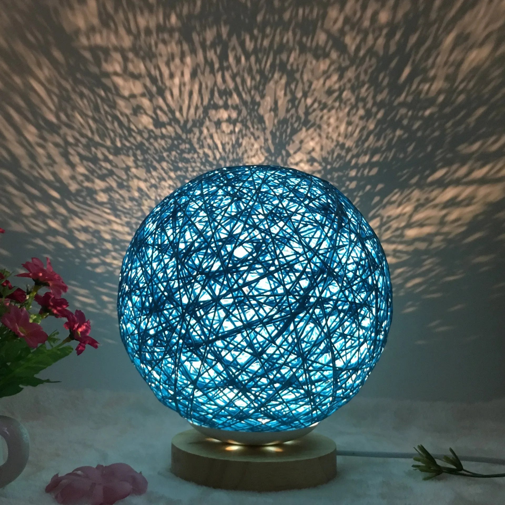 Rattan ball table lamp with woven shade and warm LED lighting on wooden surface