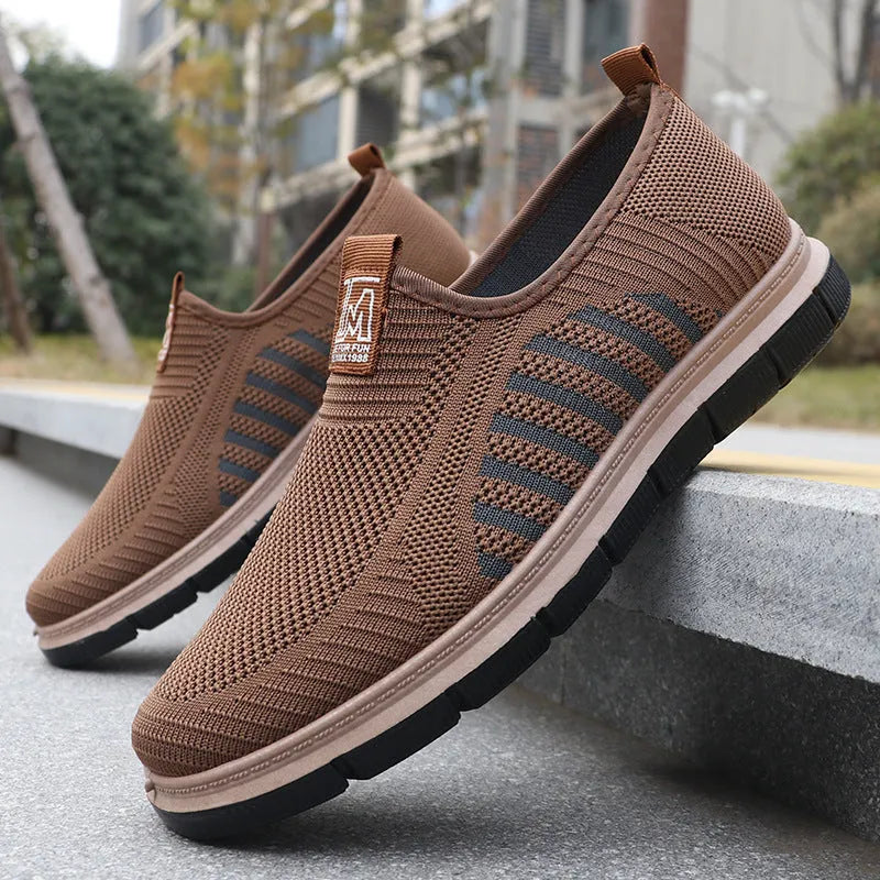Men's slip-on casual sneakers with black mesh upper, low top, flat heel, and round toe.