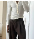Men's cream coloured ribbed long sleeve henley top with three-button placket laid flat.
