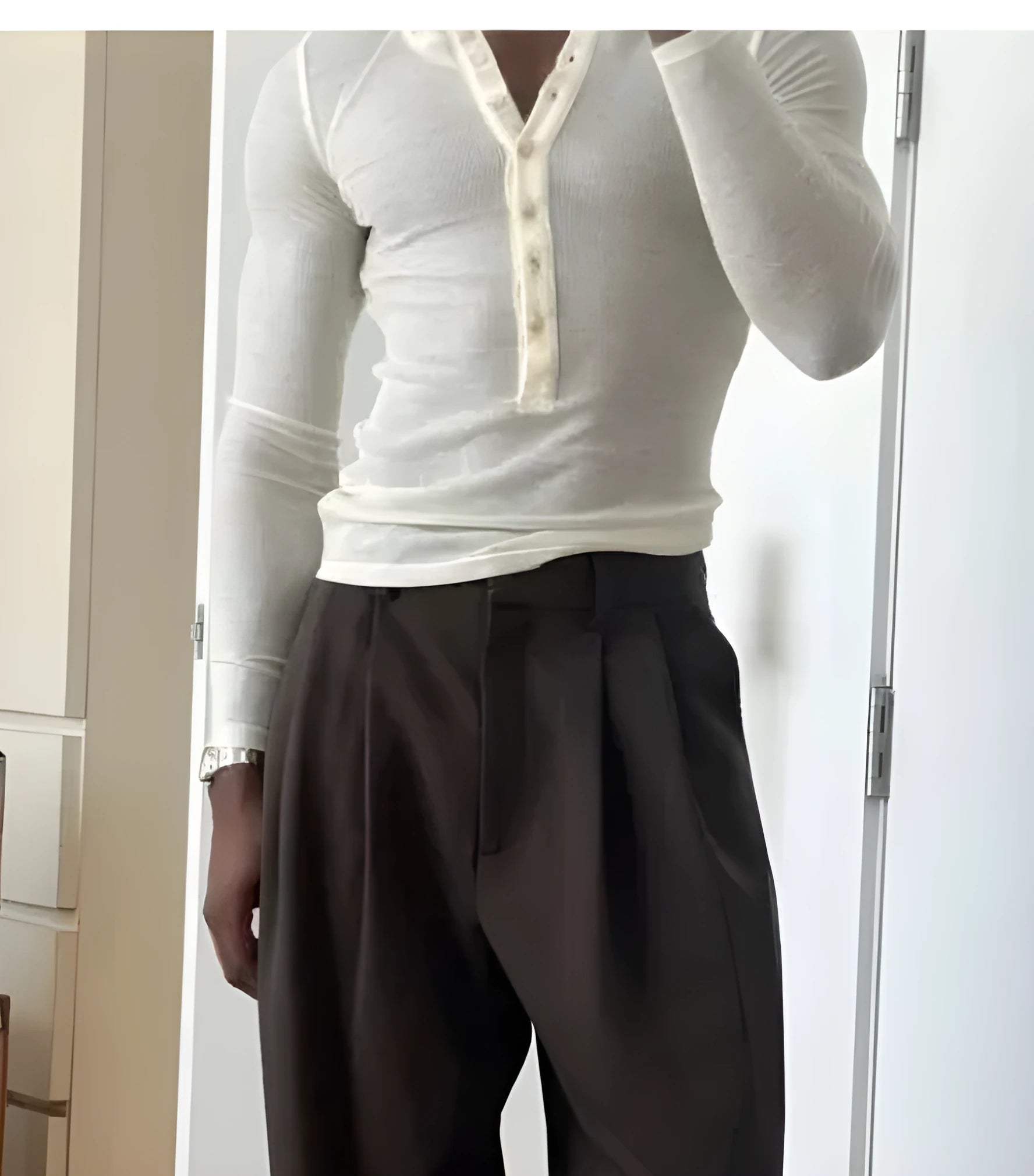 Men's cream coloured ribbed long sleeve henley top with three-button placket laid flat.