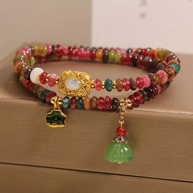 Rainbow tourmaline abacus beads double ring bracelet with lotus seedpod and flower shapes, on white background