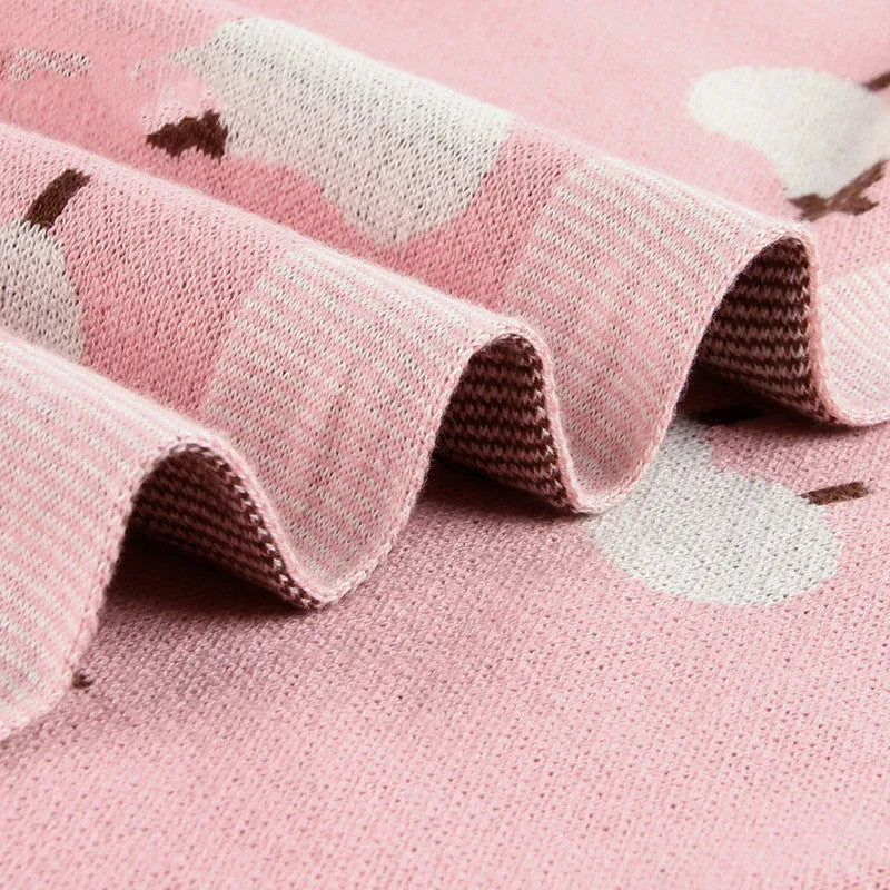Grey 100% cotton baby blanket cover draped over a sheepskin rug in a pram.