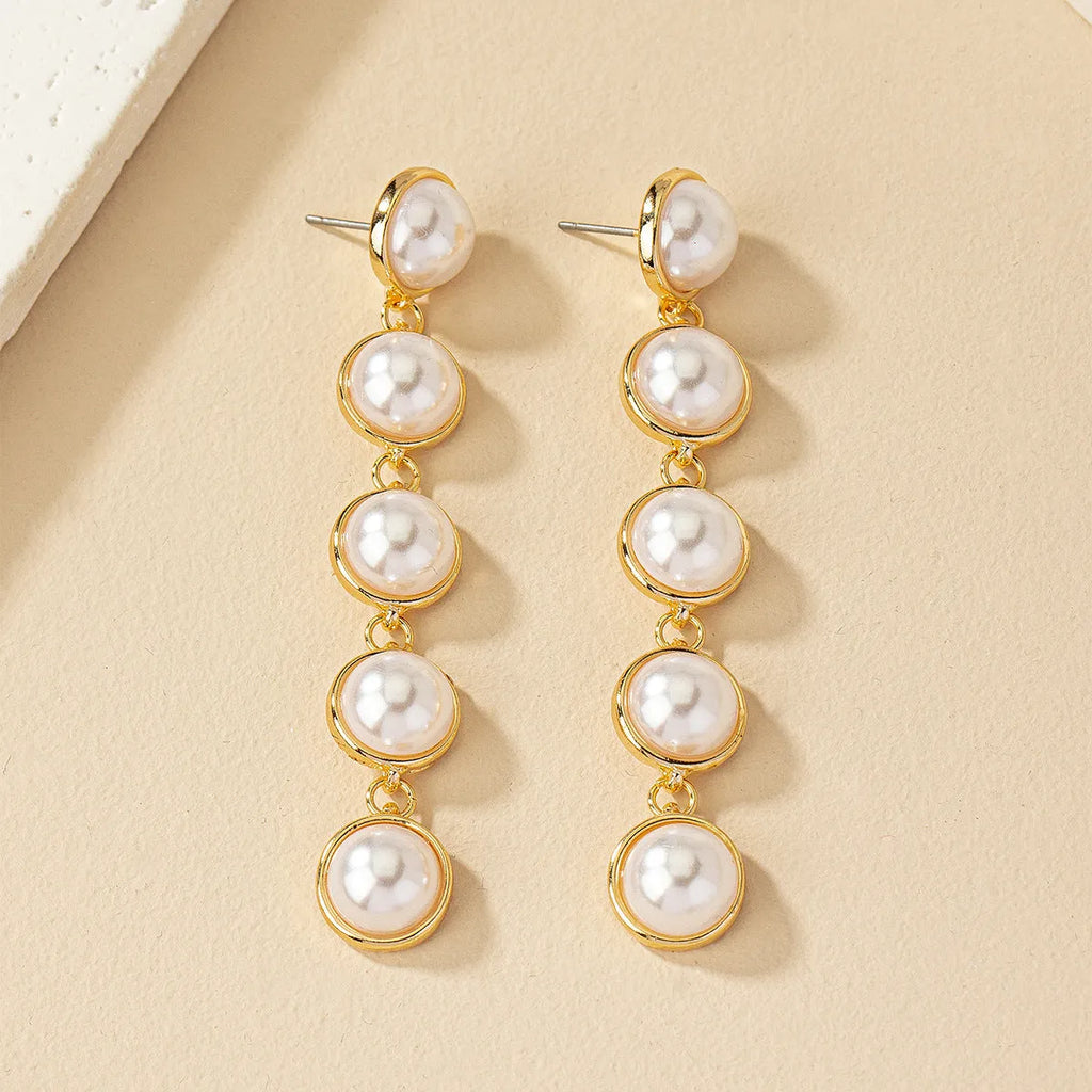 White long pearl tassel drop earrings made of electroplated metal with water flow design on white background