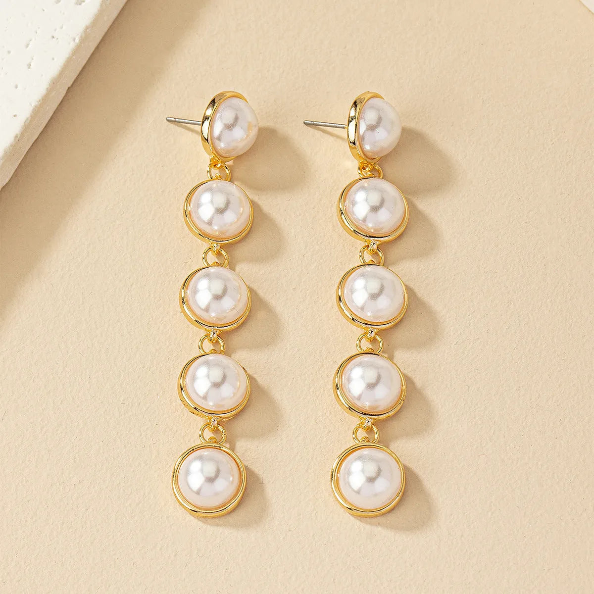 White long pearl tassel drop earrings made of electroplated metal with water flow design on white background
