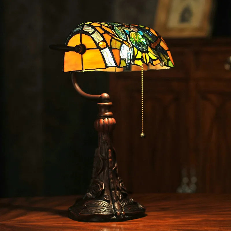 Tiffany-style table lamp with colourful stained glass shade and resin base on a desk