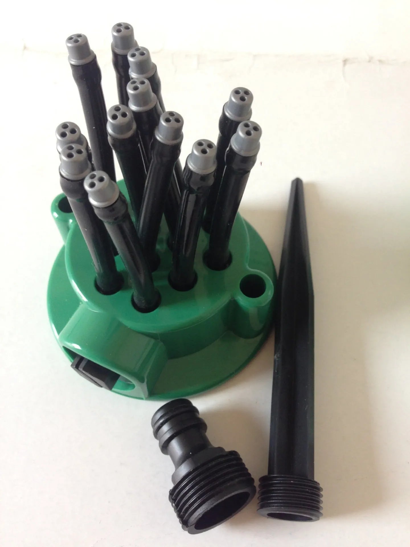 Green adjustable lawn sprinkler with multiple flexible nozzles on 9cm diameter base