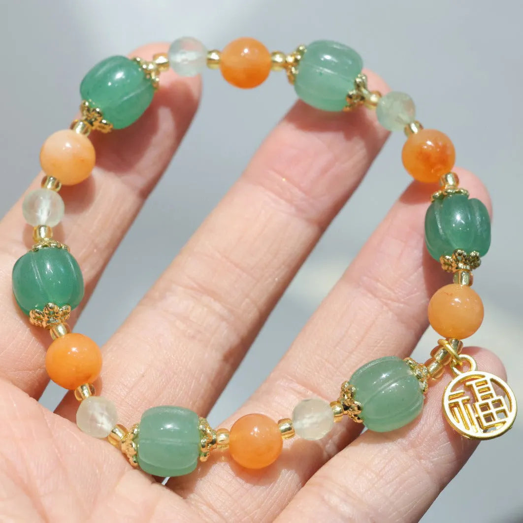 Close-up of a jade and prehnite Chinese-style pumpkin bead bracelet on a wrist.