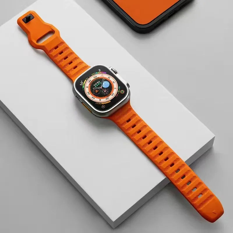 Black fluoro rubber Apple Watch strap with T-buckle closure shown detached from watch.