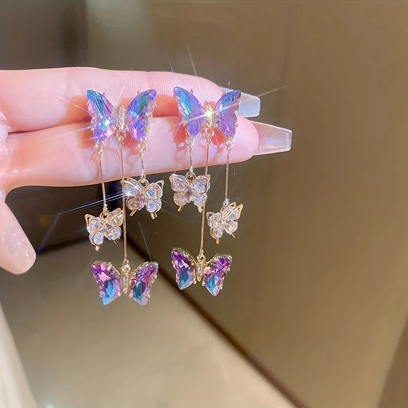 Silver Needle Blue Purple butterfly and crystal flower tassel drop earrings on a white background.