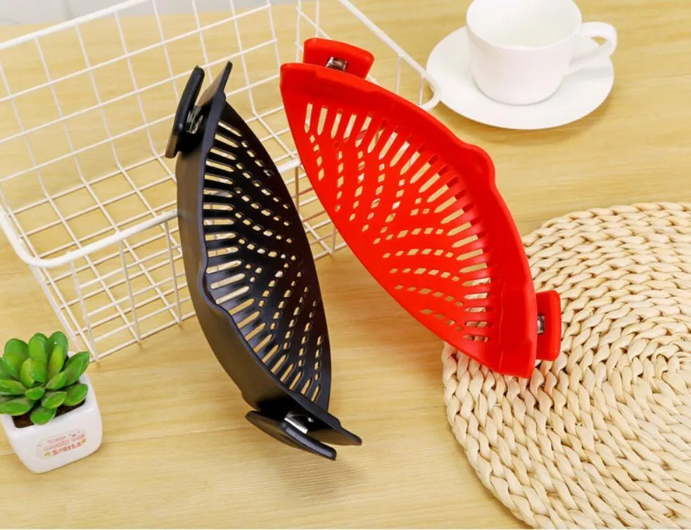Silicone clip-on colander strainer in black with stainless steel clip attached to a pot rim for draining liquid