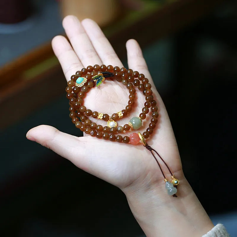 Brown Hetian Jade three-ring bracelet with butterfly and gourd charms on a wrist.