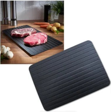 Black aluminium fast defrosting tray with silica gel feet on a kitchen countertop.
