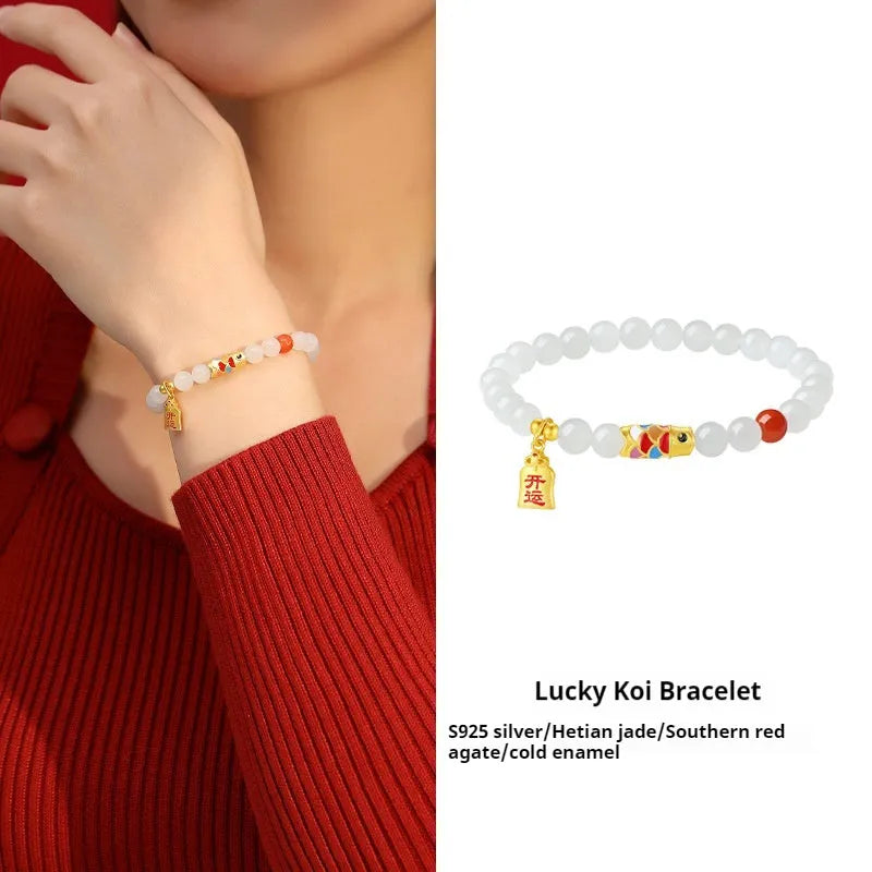 Close-up of a sterling silver bracelet with a blue and orange cold enamel koi fish charm set with Hetian jade.