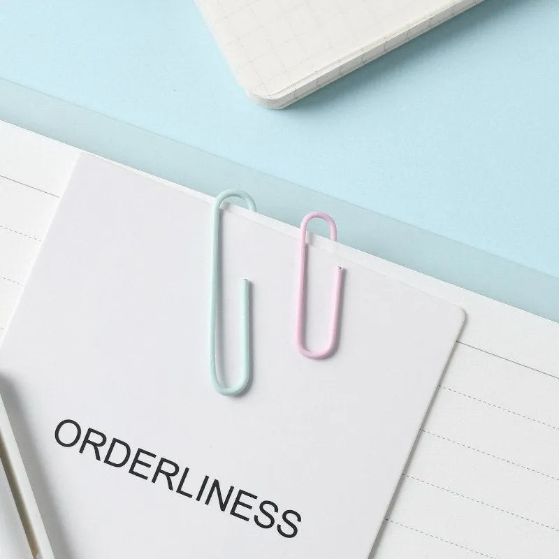 Macaron-color paper clips in pastel shades including pink, green, and purple on a white desk