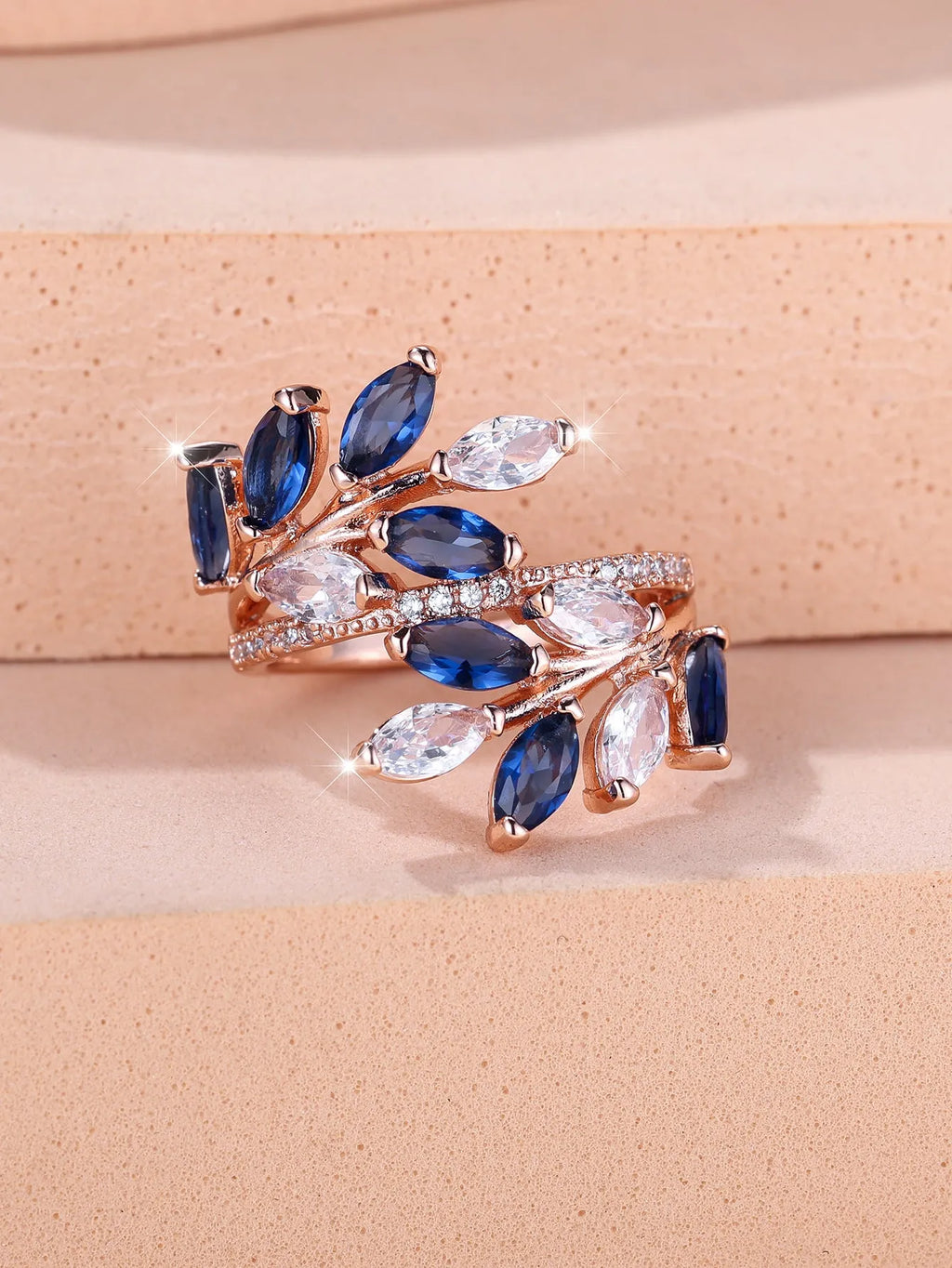 Adjustable copper leaf fashion ring with a central zircon stone on a model's hand, showing rose gold and platinum colour variants.