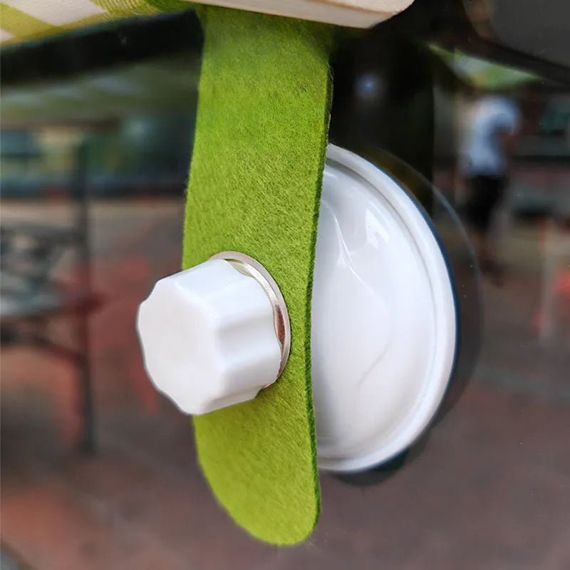 Green wooden cat window hammock with suction cups attached to glass, showing a removable linen mat.