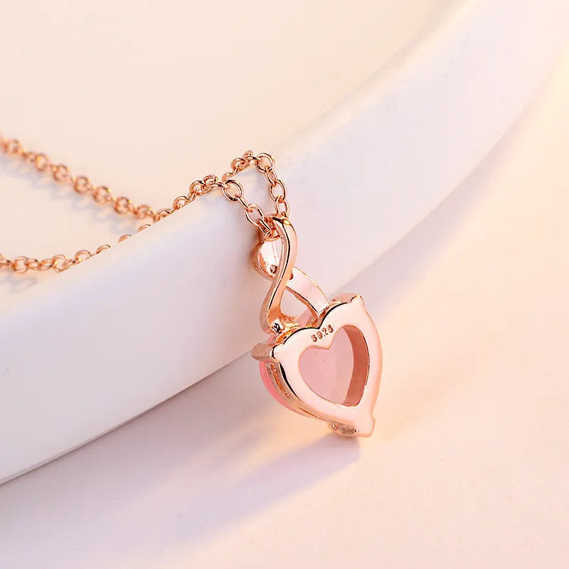 Women's pink heart crystal pendant necklace with rose gold chain on white background