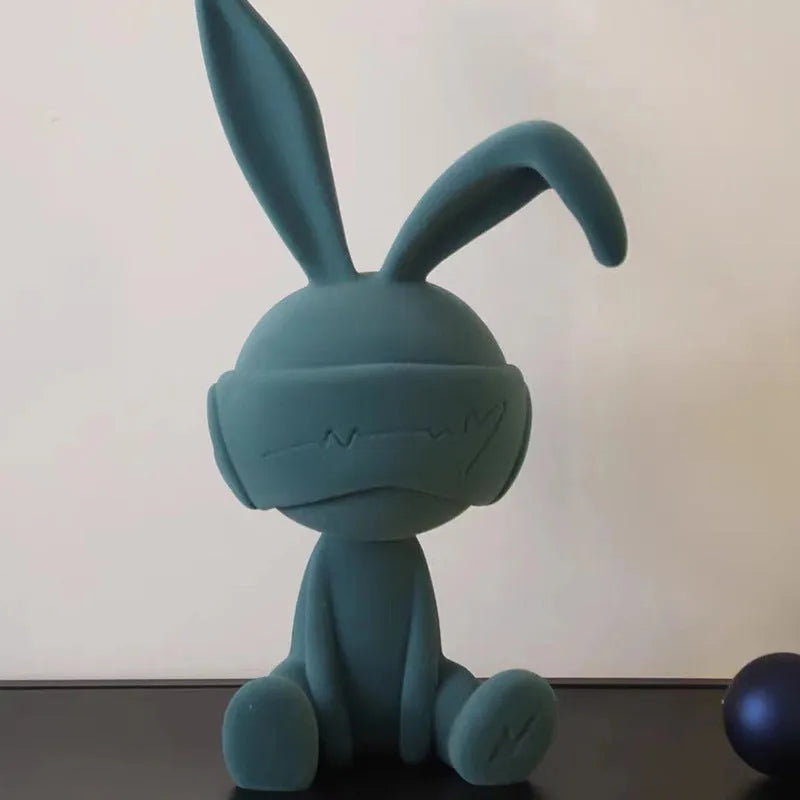 Green suede blindfold rabbit resin table ornament on a wooden surface.