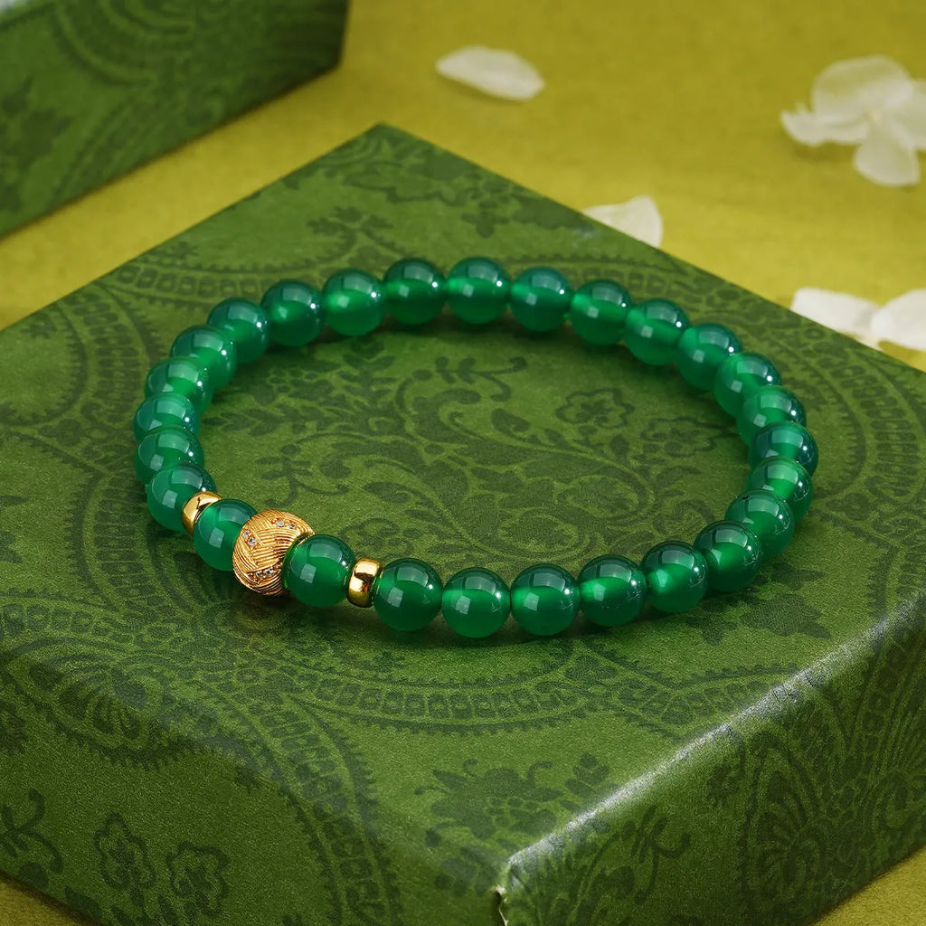 Close-up of a women's bracelet with a green agate stone on a two-tone silver and gold-plated chain.
