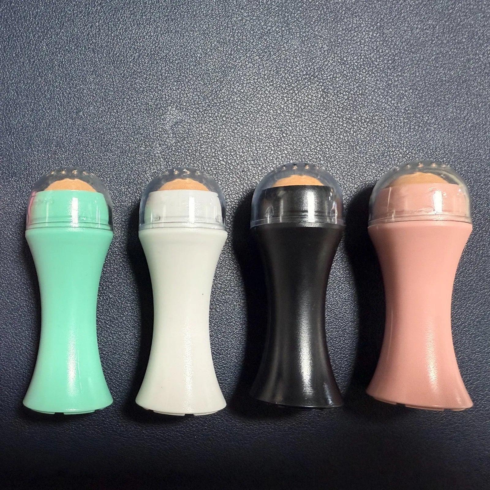 Volcanic stone portable oil absorbing facial roller in choice of colours on a white background.